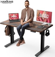 a man sitting at a desk with two laptops