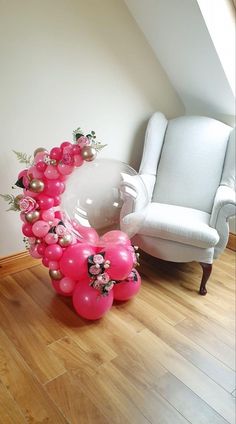 a balloon arch in the shape of a crescent with pink flowers and pearls on it