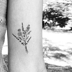 a black and white photo of a flower tattoo on the left inner arm, with small flowers growing out of it