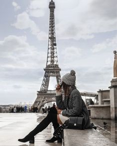 a woman sitting on top of a stone bench next to the eiffel tower