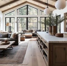 a living room filled with lots of furniture and large windows in the middle of it