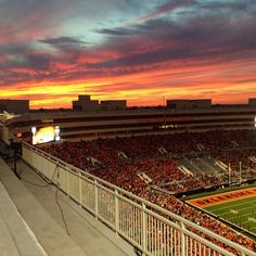 an empty football stadium filled with fans at sunset