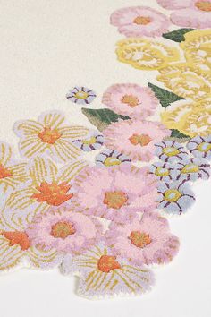 a close up of flowers on a white surface with pink, yellow and blue colors