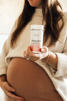 a pregnant woman holding a jar of vitamins