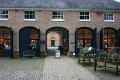 an old brick building with lots of windows and benches in front of the entrance to it