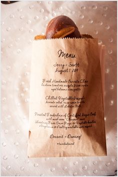 a brown paper bag with some food inside of it on a white tablecloth covered surface