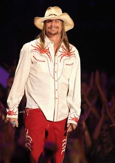 a man in a cowboy hat and red pants walks down the runway at a fashion show