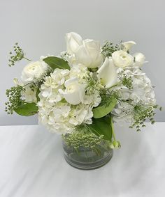 a vase filled with white flowers and greenery