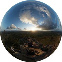 the sun is reflected in an image of rocks and trees, as well as clouds