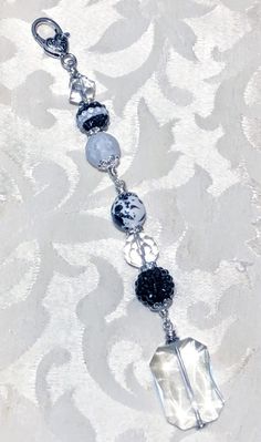 a silver and black beaded bracelet on a white tablecloth with an ornate design