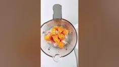 a blender filled with oranges sitting on top of a white counter next to a knife