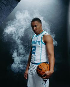 a man holding a basketball while standing in front of a smokestack background with his hands on his hips