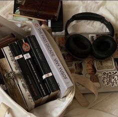 there are many books and headphones on the bed