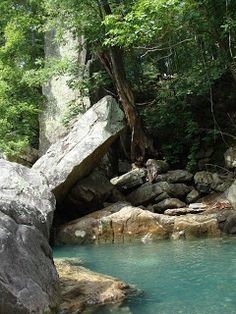 the water is blue and green in this rocky riverbed with large rocks on both sides