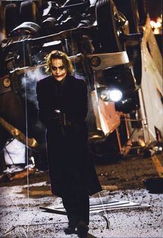 the joker is standing in front of a pile of junk