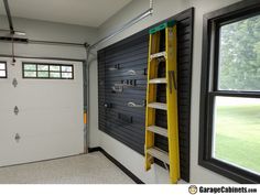 a yellow ladder is hanging on the wall in front of a garage door with windows