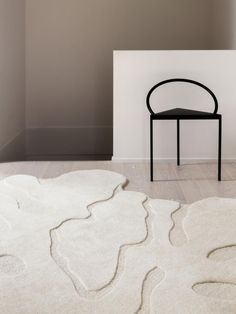 a chair sitting on top of a wooden floor next to a white rug and wall