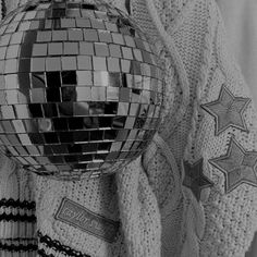 black and white photograph of a disco ball on a blanket with stars around it,