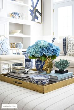 a living room filled with blue and white flowers on top of a coffee table next to a couch