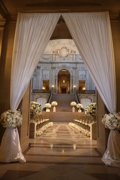 the aisle is decorated with flowers and white draping for an elegant wedding ceremony