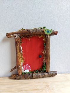 a small red door in the shape of a log with a green bird perched on it