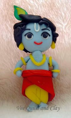 a small blue figurine sitting on top of a white blanket