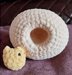 a small stuffed animal next to a crocheted donut on a purple blanket