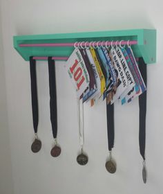 a green shelf with several medals hanging from it's hooks and two coin holders