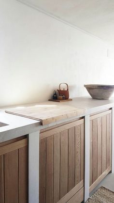 a wooden counter top sitting next to a bowl on top of a white countertop