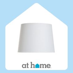 a white lamp shade sitting on top of a light blue background with the at home logo below it