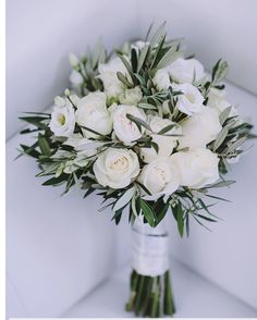 a bouquet of white flowers sitting on top of a white couch next to a window