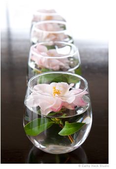 two vases filled with flowers on top of a wooden table next to each other