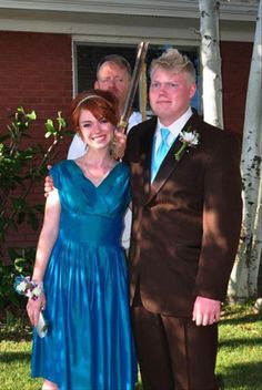 a man in a suit and tie standing next to a woman in a blue dress