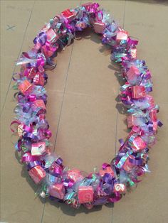 a circular object made out of plastic wrapped in purple and pink ribbons on top of cardboard