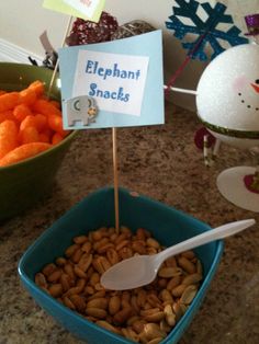 a bowl filled with peanuts next to a sign that says elephant snacks on top of it