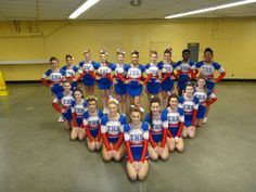 a group of cheerleaders posing for a photo in the middle of a gym