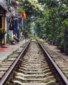 an old train track running through the middle of a town with people walking on it