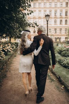 an older man and woman walking down a path