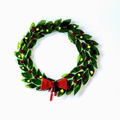 a green wreath with red bows and yellow berries on it is displayed against a white background