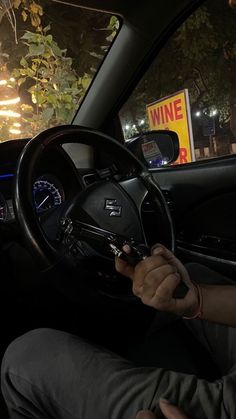 a man sitting in the driver's seat of a car with his hand on the steering wheel