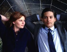 a man and woman are posing for a photo together in front of a mosaic wall