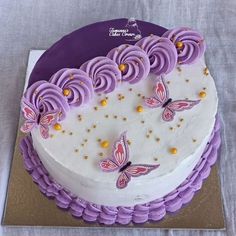 a white cake with purple icing and butterflies on it