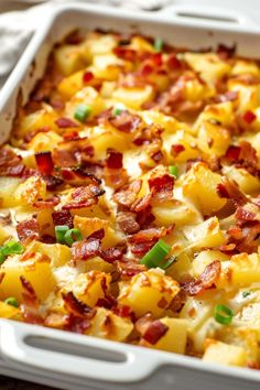 a casserole dish with potatoes and bacon in it on a wooden table top