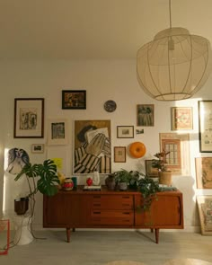 a living room filled with furniture and pictures on the wall next to a light fixture