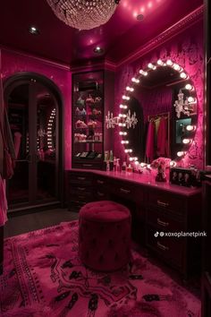 a pink room with a vanity, mirror and chandelier filled with lights in it