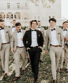 a group of men standing next to each other in front of a white building wearing suits