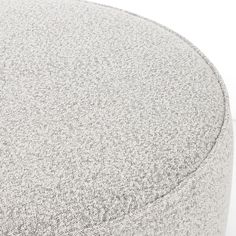 a close up view of the back of a grey and white round ottoman with buttons on it