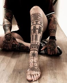 a man sitting on the floor with tattoos on his legs