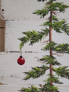 a painting of a pine tree with a red ornament hanging from it's branch