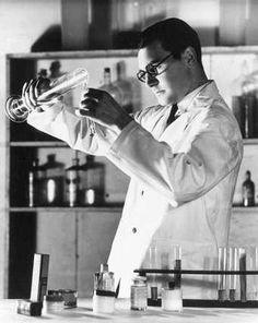 a man in a lab coat pouring liquid into beakles